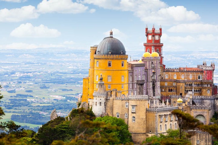 a castle surrounded by a body of water with Pena Palace in the background