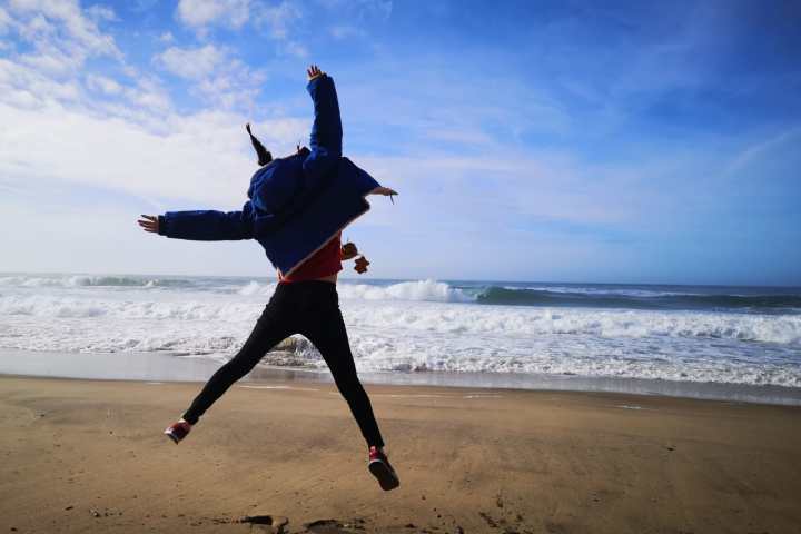 a man flying through the air on top of a sandy beach