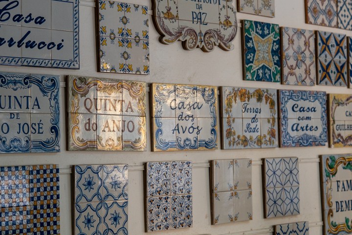 A wall displaying various decorative Portuguese tiles with text and intricate patterns in blue and gold hues.