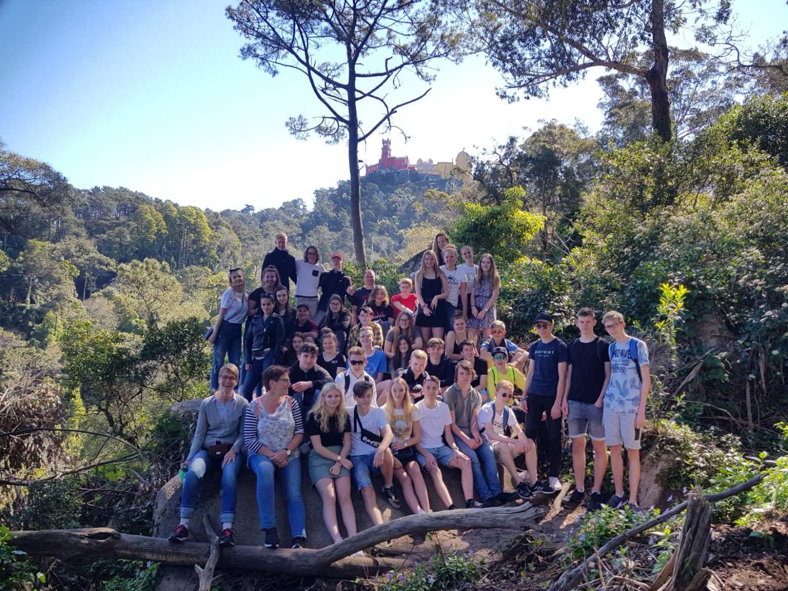a group of people standing in front of a tree posing for the camera