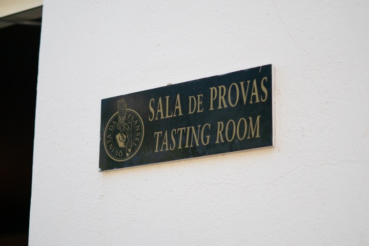 Wall-mounted sign reads 'Sala de Provas Tasting Room' with a logo on a white background.