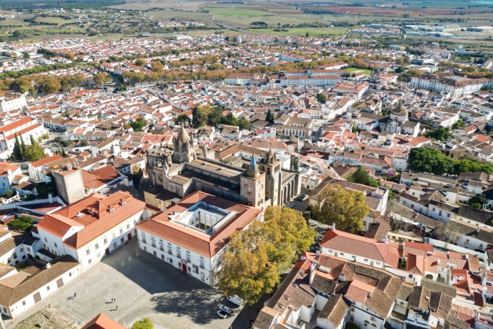 Aerial view of a historic city with red-roofed buildings and a central cathedral.