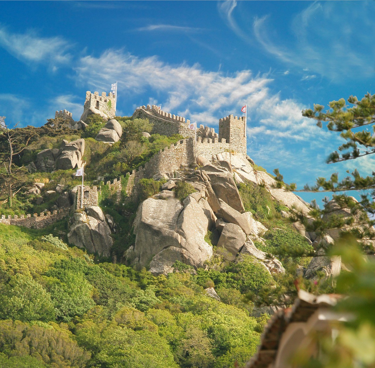 Ancient stone castle on a rocky hill with blue sky and clouds.