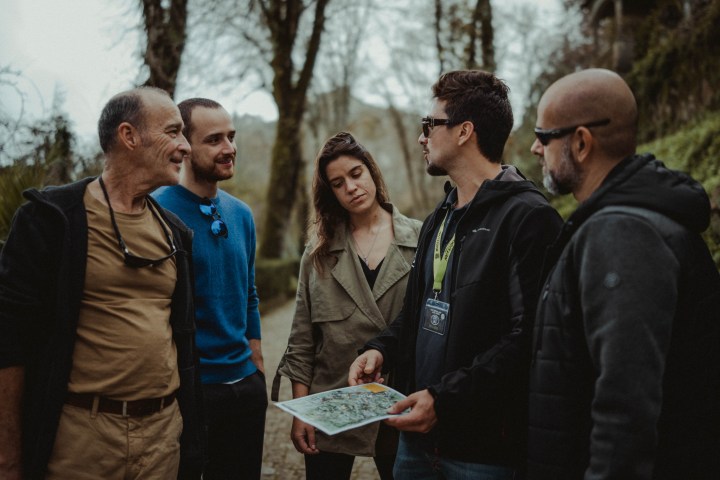 Five people standing outdoors discussing a map.