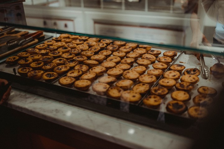 Display of many small tarts on a tray behind a glass counter.